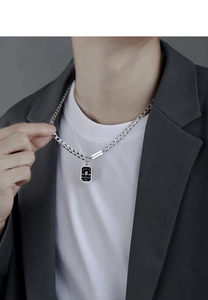 Detail of male model wearing layered silver pendants with BARDIAN and Good Luck engraving
