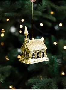 Detailed view of a golden church-shaped Christmas ornament with warm festive lighting