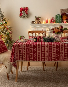 Detailed close-up of Christmas tablecloth featuring red deer and tree patterns with lace edge