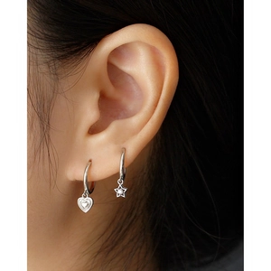 Close-up of S925 silver heart and star pendant earrings worn by a model