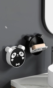 Detail view of wall-mounted panda soap dish with flip lid and drainage tray in a bathroom