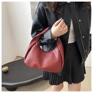Detail of red woven hobo bag with knotted handle worn with a black leather jacket