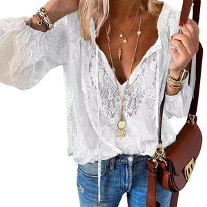 Detalle de blusa bohemia de encaje blanco con escote en V profundo y lazos con borlas