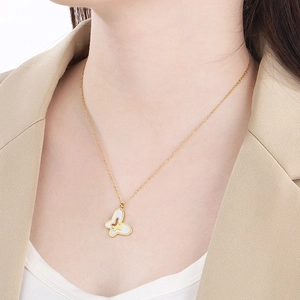 Gold chain necklace with white shell butterfly pendant worn by a model in a beige suit