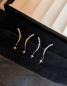 Detailed close-up of star-shaped zircon earrings in gold and silver finishes