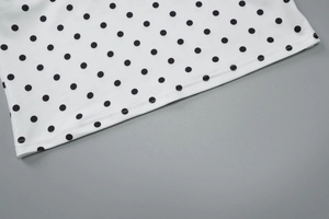 Close-up of black polka dot pattern and precise stitching on white summer top fabric