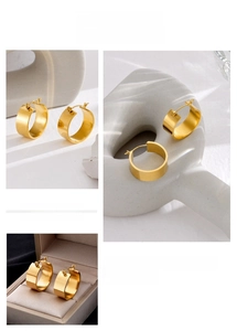 Detail of wide gold hoop earrings with polished metal texture and secure snap closure