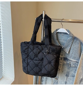 Detail of black quilted tote bag featuring floral embroidery and matching small zipper pouch