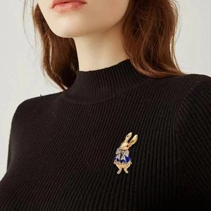 Detailed view of a golden bunny brooch with blue outfit and rhinestones on a blazer