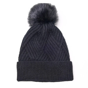 Detail of black cable knit beanie featuring thick V-pattern texture and large faux fur pom