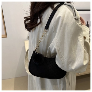 Détail du sac bandoulière en velours noir matelassé avec chaîne et pompon en fourrure