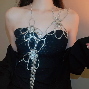 Detailed view of silver flower body chain with crystal tassels on a black top