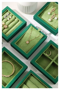 Deep green velvet jewelry tray set with ring slots and necklace dividers on white marble