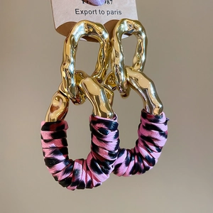 Macro detail of geometric leopard print fabric and gold textured metal link earrings