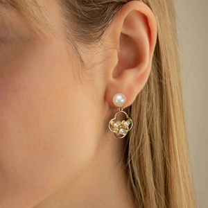 Detailed view of S925 silver pearl drop earrings with gold floral petal design on model