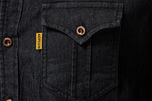 Detailed macro view of black denim shirt fabric with wood buttons and pocket stitching