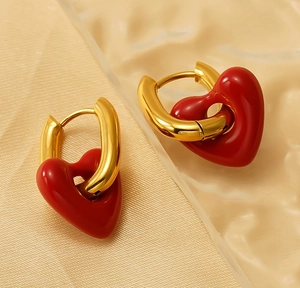Detail of vintage gold U-shaped earrings with red enamel heart charms on silk
