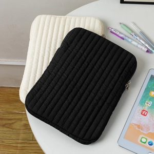 Close-up of quilted laptop and tablet sleeve cases in black and off-white colors