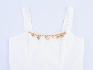 Close-up detail of white beach dress featuring decorative shell and starfish pendant charms