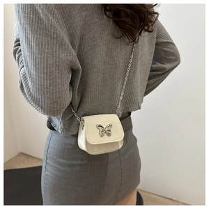 Back view of model wearing a white leather crossbody bag with silver butterfly buckle