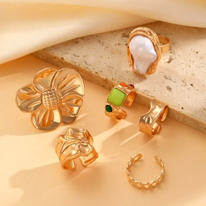 Detail of a 6-piece vintage gold ring set with baroque pearls and floral metal textures