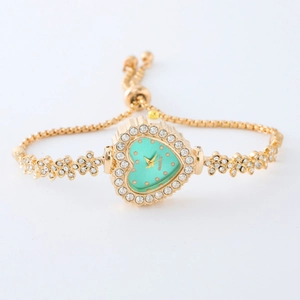 Close-up of gold heart bracelet watch with turquoise dial and sparkling crystal bezel