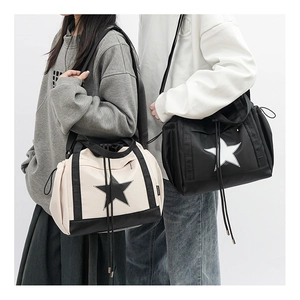 Detail view of cream and black star shoulder bags with side drawstring on two models