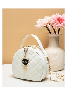 Close-up of white quilted round crossbody bag with cute cat charm and gold chain strap