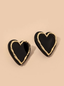 Macro detail of vintage heart earrings featuring black enamel and wavy gold metal borders