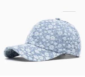 Detail of light blue denim baseball cap with white floral pattern and curved brim