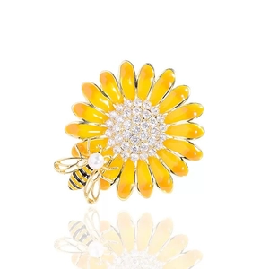 Macro view of enamel daisy flower brooch with sparkling diamond center and pearl bee