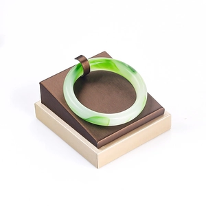Elegant green jade bracelet on a premium brown display stand with a square gift box