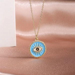 Detail shot of a golden Evil Eye pendant with blue enamel and pavé stones on pink silk