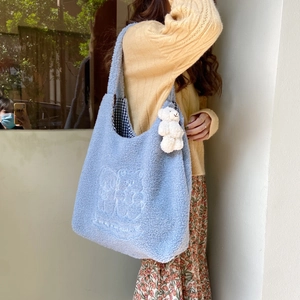 Detail of light blue plush tote bag featuring bear embroidery and cute bear charm