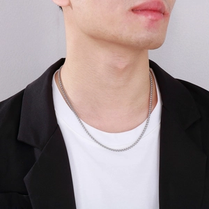 Close-up of a silver stainless steel wheat chain necklace worn by a male model