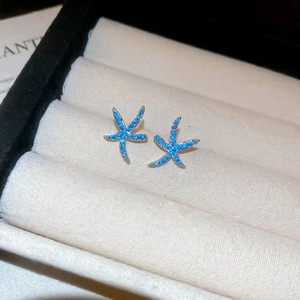 Dettaglio macro di orecchini a lobo stella marina blu con cristalli in scatola regalo