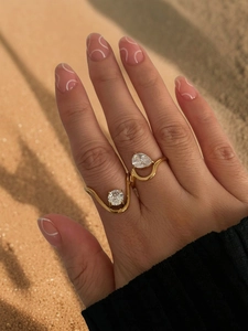 Detail of gold geometric rings with round and pear cut zircons on a beach background