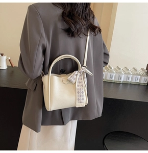 Detail of off-white lychee texture bucket bag with silk scarf on a grey blazer model