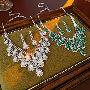 Detailed shot of emerald and clear crystal teardrop necklace and earring sets on a tray
