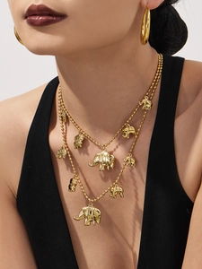 Détail de colliers multicouches dorés avec pendentifs éléphants et chaînes à billes portés
