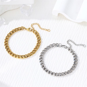 Close-up of gold and silver Cuban link bracelets with extension chains on white texture