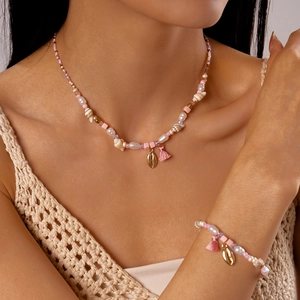 Close-up of beaded necklace and bracelet with seashells, pearls and pink tassels