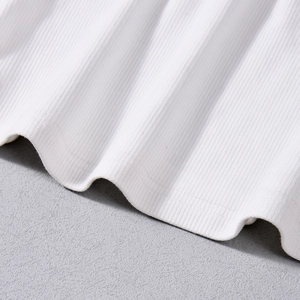 Détail macro du tissu blanc côtelé montrant la texture verticale et la finition soignée