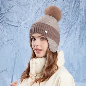 Winter knitted earflap hat with pom-pom in beige and brown color-blocking for women