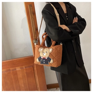 Detail of brown quilted tote bag with teddy bear embroidery and beige shoulder strap