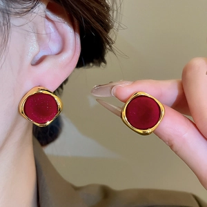 Detailed view of red flocking geometric round earrings with gold metal frames on model