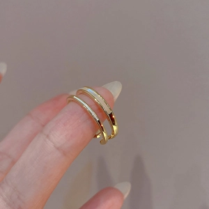 Detail of a double-layer gold plated ring with white enamel accents on a finger