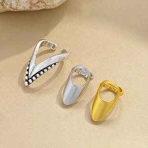 Lot de trois bagues à ongles tendance dorées, argentées et antiques sur fond de sable chaud