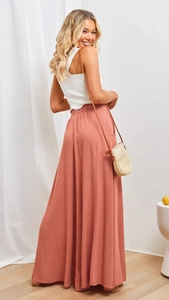 Close-up of coral pink wide-leg trousers showing waist elasticity and side pockets
