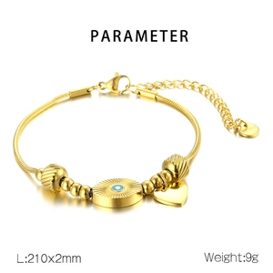 Detail view of gold heart and evil eye charms on a stainless steel snake chain bracelet
